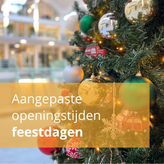 Close-up van een kerstboom met mooie kerstballen erin. De Melkfabriek zie je onscherp op de achtergrond.